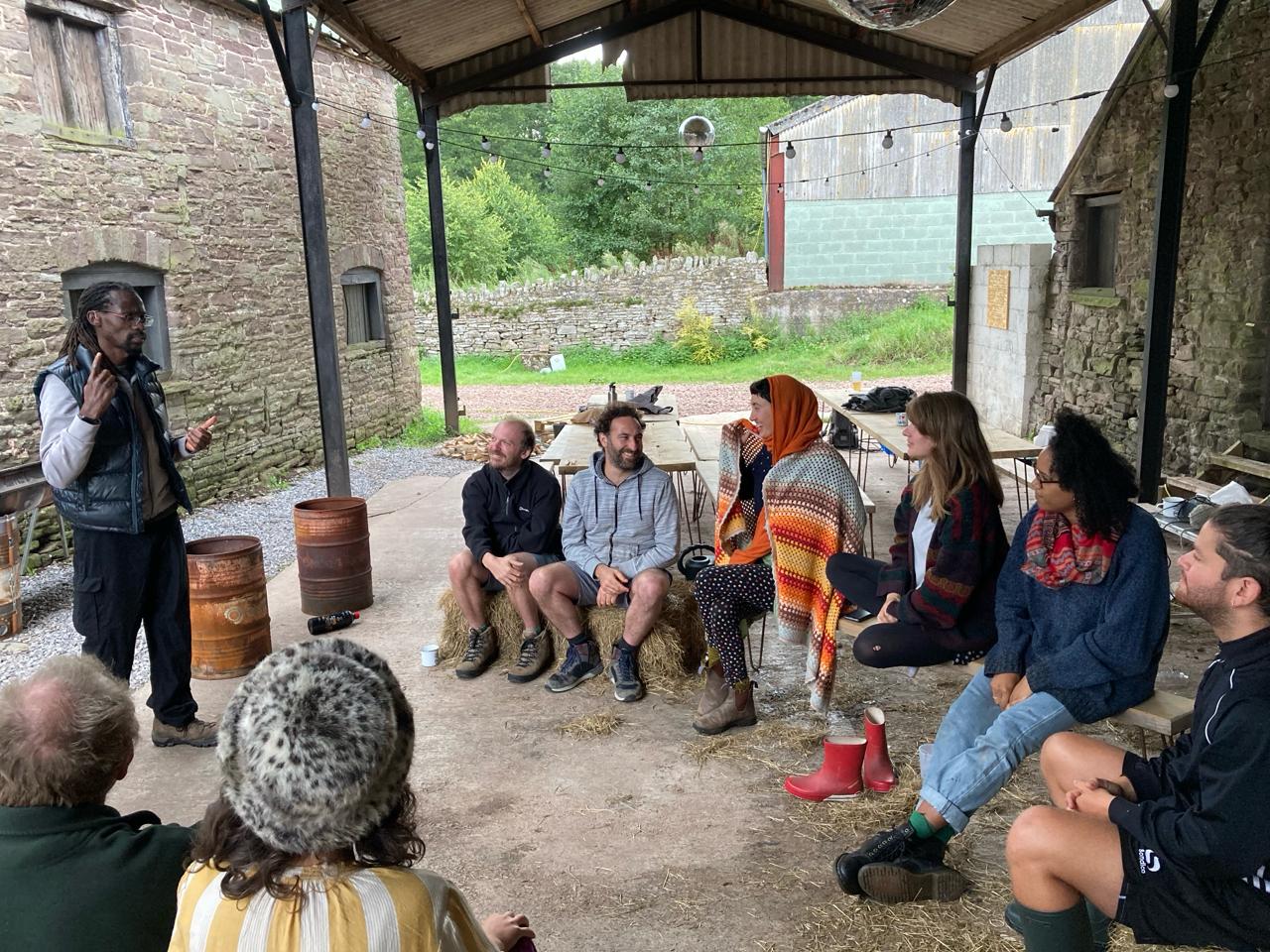 Kwame Afrik teaching a Deaf awareness workshop outdoors to a seated group